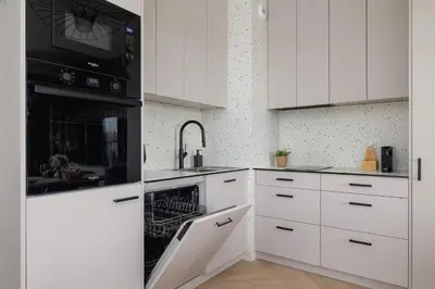 a white kitchen with white cabinets and a dishwasher at Prandoty 10C Cozy Apartment with Balcony & Parking in Krakow by Noclegi Renters in Kraków