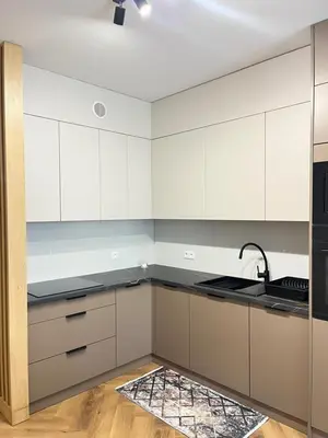 a kitchen with white cabinets and a black counter top at Apartament M16 in Limanowa