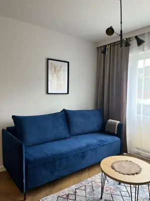 a blue couch in a living room with a table at Apartament M16 in Limanowa