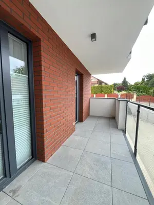 a building with a brick wall and a patio at Apartament M16 in Limanowa