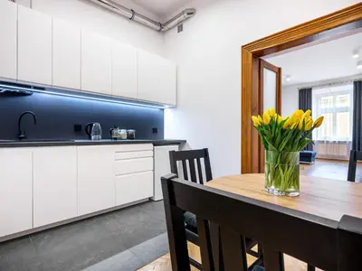 a kitchen with a wooden table with yellow flowers in a vase at Golden Market Square Apartments by Tyzenhauz in Kraków