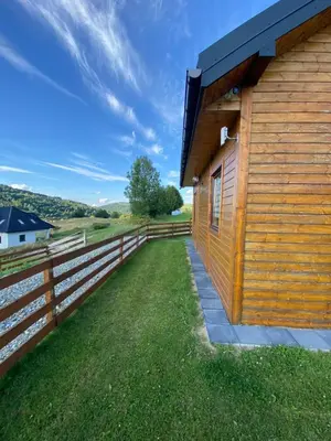 a wooden building with a fence next to it at Domek całoroczny w Porębie wielkiej z widokiem na góry in Poręba Wielka