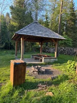 a wooden gazebo in a field with a fire pit at Apartament 1 w Kocierzu in Kocierz Rychwałdzki
