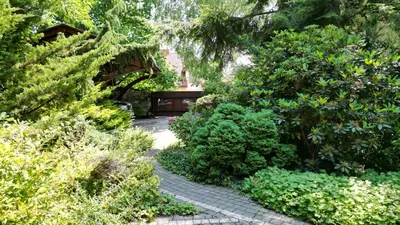 a garden with a brick walkway with bushes and trees at Apartament 294 W Cieniu Drzew by BookingHost in Giebułtów