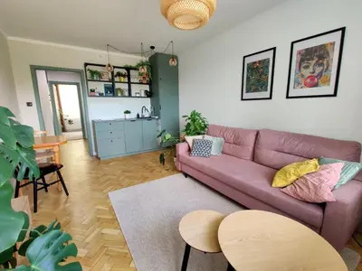 a living room with a pink couch and a kitchen at Positive Vibes in Kraków