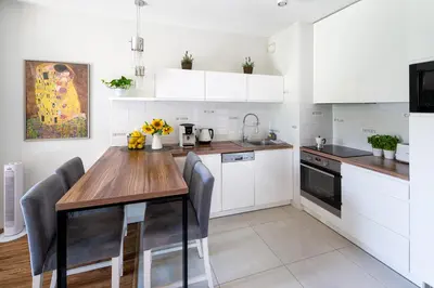 a kitchen with white cabinets and a wooden table at Chick 1bdr loft in Krakow's city centre in Kraków