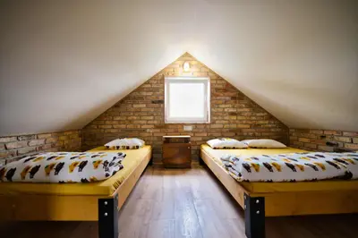 a attic room with two beds and a brick wall at 3 Stodoły - domek 2 in Zator