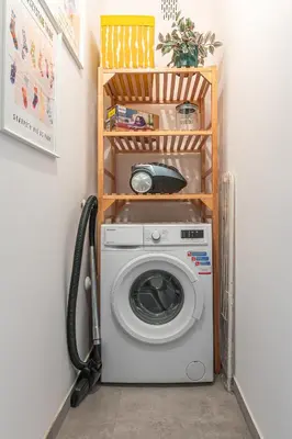 a washing machine in a laundry room with a shelf at Apartament HoliStay in Oświęcim