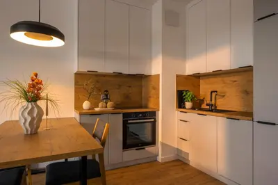 a kitchen with white cabinets and a wooden table at Apartamenty Lew Invest obok Rynku Głównego, Parking w cenie in Kraków