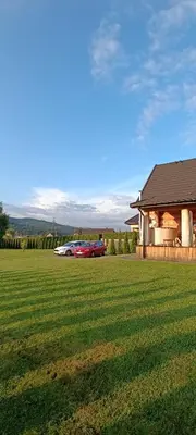 a car parked in a field next to a house at Chata Gilowicka - Beskid Żywiecki in Gilowice