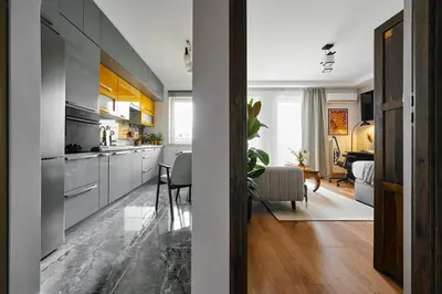 a kitchen with gray cabinets and a dining room at UR4N Apartment - Czarnogórska in Kraków