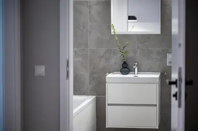 a bathroom with a white sink and a white cabinet at Apartamenty Lew Invest Wrocławska, Parking w cenie! in Kraków
