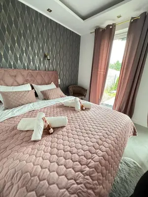 a bedroom with a large pink bed with towels on it at Chill&Love Apartament