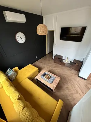 a living room with a yellow couch and a clock at La Ville - Jaune in Zator