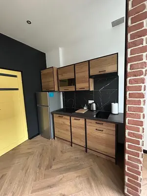 a kitchen with wooden cabinets and a brick wall at La Ville - Jaune in Zator