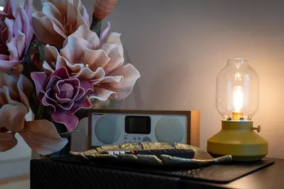 a table with a clock and a lamp and flowers at LIFESTYLE Apartments in Bochnia