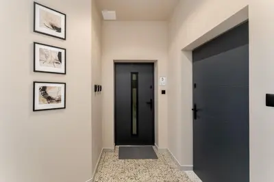 a hallway with a black door and pictures on the wall at LIFESTYLE Apartments in Bochnia
