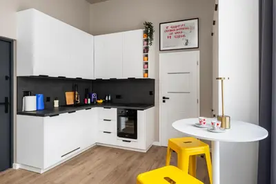 a kitchen with white cabinets and a white table and yellow stool at LIFESTYLE Apartments in Bochnia