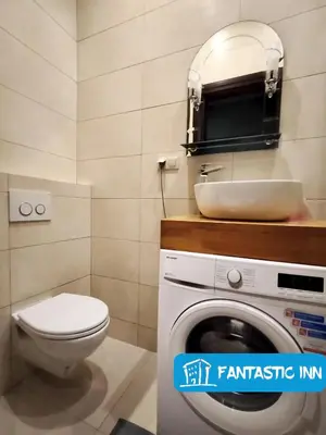 a bathroom with a toilet and a sink and a washing machine at Fantastic-Inn Kraków - Słowackiego in Kraków