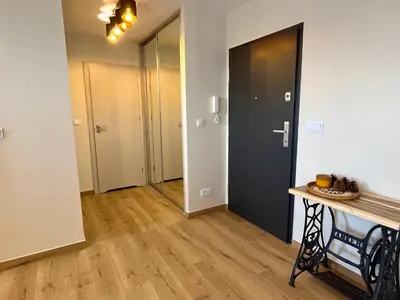 a hallway with a door and a table in a room at Nowy apartament Saska, z parkingiem in Kraków