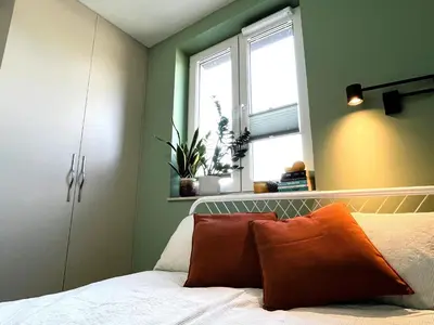 a bedroom with green walls and a bed with orange pillows at Nowy apartament Saska, z parkingiem in Kraków