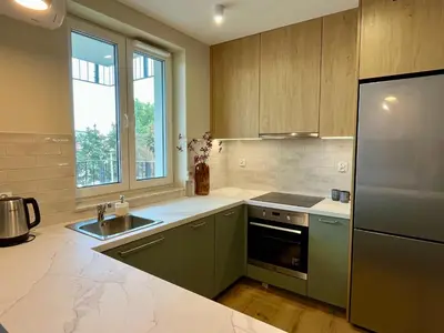 a kitchen with green cabinets and a sink and a refrigerator at Nowy apartament Saska, z parkingiem in Kraków