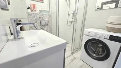 a white bathroom with a washing machine and a sink at Blue Salt in Wieliczka