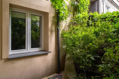 a window on the side of a building next to a bush at Park Krakowski Comfy Studio by BookingHost in Kraków