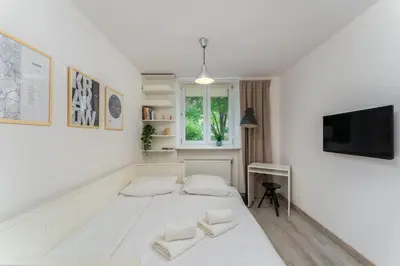 a white room with a bed and a tv at Park Krakowski Comfy Studio by BookingHost in Kraków