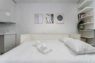 a white bedroom with two towels on a bed at Park Krakowski Comfy Studio by BookingHost in Kraków