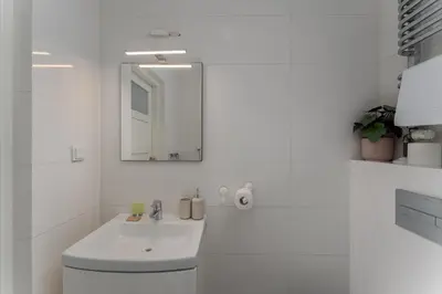 a white bathroom with a sink and a mirror at Park Krakowski Comfy Studio by BookingHost in Kraków
