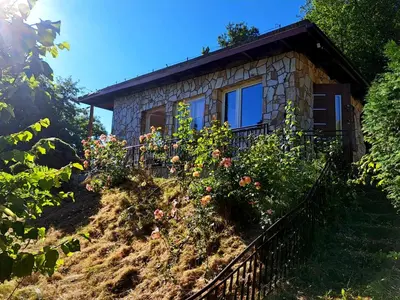 a small stone house on a hill with flowers at Dom z tarasem wśród pól i lasu - przestronny salon, blisko natury in Lubień