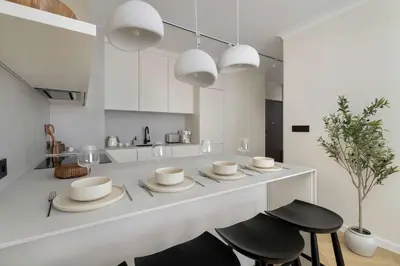 a kitchen with a white counter with stools and white cabinets at Prandoty Stylish Apartment with Balcony & Parking in Cracow Old Town by Renters Prestige in Kraków