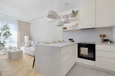 a kitchen with white cabinets and a living room at Prandoty Stylish Apartment with Balcony & Parking in Cracow Old Town by Renters Prestige in Kraków