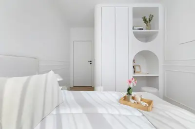a white bedroom with a bed with a tray with flowers on it at Prandoty Stylish Apartment with Balcony & Parking in Cracow Old Town by Renters Prestige in Kraków