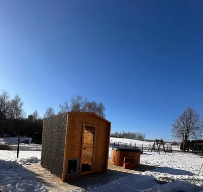 a small wooden shed in a snow covered field at Apartamenty TUTERRA III in Zabagnie