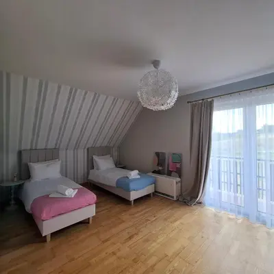 a bedroom with two beds and a chandelier at Apartamenty TUTERRA III in Zabagnie