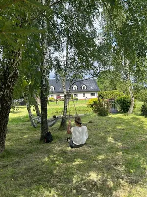 a man sitting in the grass under a tree at Apartamenty TUTERRA III in Zabagnie