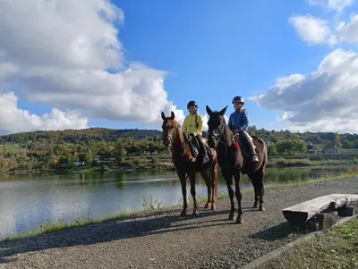 two people riding horses next to a river at Domek z widokiem na góry in Targoszów