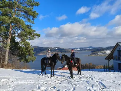 two people are riding horses in the snow at Domek z widokiem na góry in Targoszów