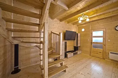 a log cabin with a staircase and a tv at Domek z widokiem na góry in Targoszów