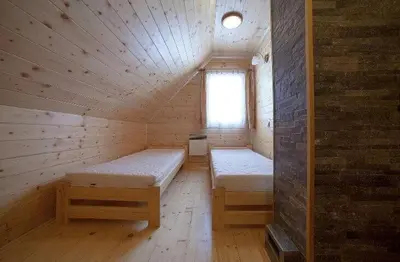 a room with two beds in a wooden cabin at Domek z widokiem na góry in Targoszów