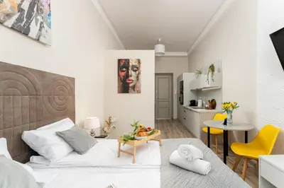 a bedroom with a bed and a kitchen with yellow chairs at Malila Premium Apartments Cracow Sebastiana 27 in Kraków