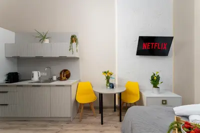a kitchen with a table and two yellow chairs at Malila Premium Apartments Cracow Sebastiana 27 in Kraków