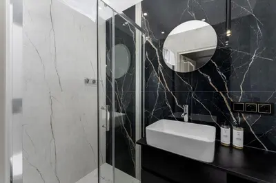 a bathroom with a shower and a sink and a mirror at Malila Premium Apartments Cracow Sebastiana 27 in Kraków