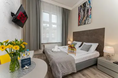 a bedroom with a bed and a table with flowers at Malila Premium Apartments Cracow Sebastiana 27 in Kraków