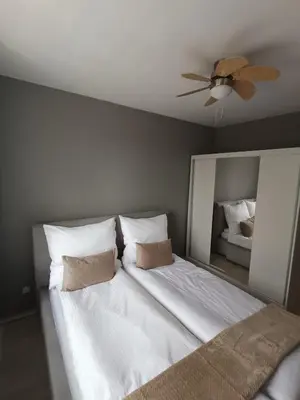 a bedroom with a white bed with a ceiling fan at Apartament Maria in Oświęcim