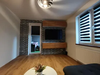 a living room with a brick fireplace and a tv at Apartament Maria in Oświęcim