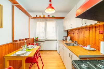 a kitchen with white cabinets and a table and a sink at Kraszewskiego Apt - Balcony, Park & River nearby - by Rentujemy in Kraków