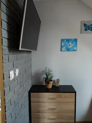 a room with a dresser with a tv on a brick wall at Słoneczne apartamenty Zator blisko Energylandii in Zator